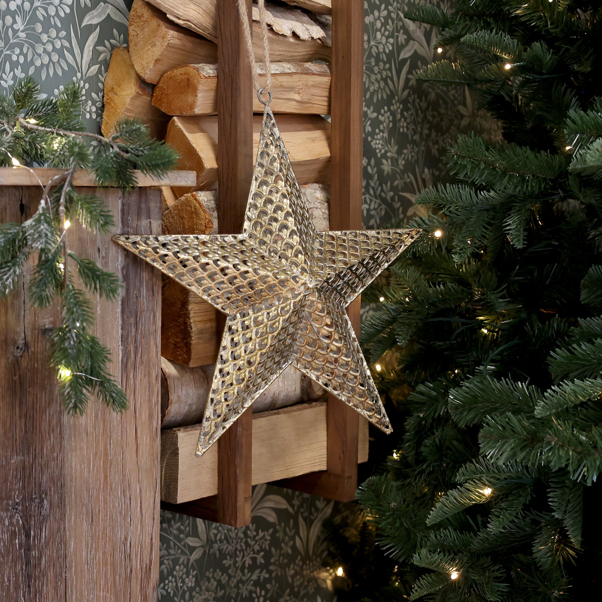 Decorative star hanging on a wooden wall with Christmas tree and lights in the background