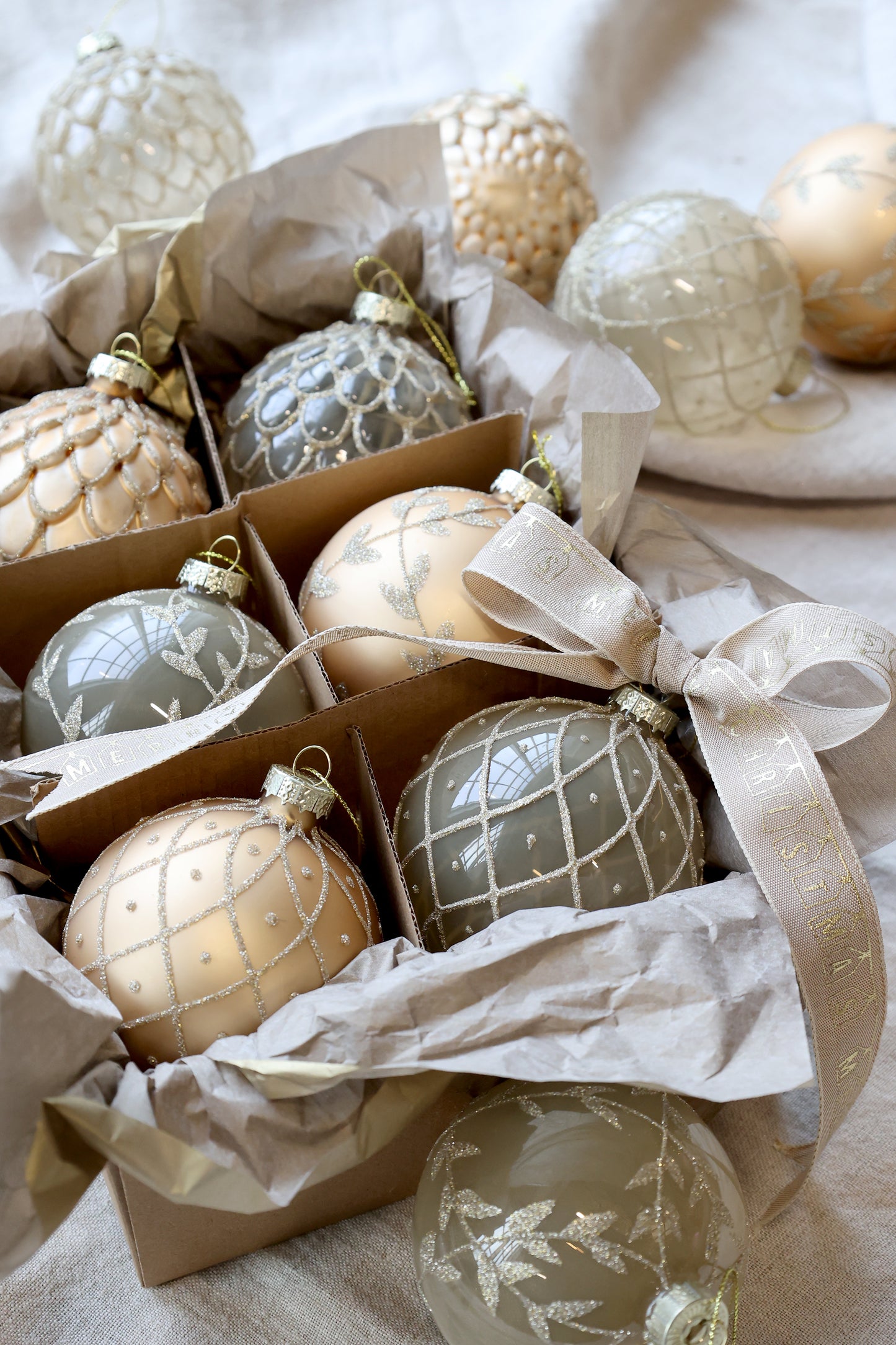Decorative Christmas ornaments in a box with tissue paper on a light background. Generosa Home