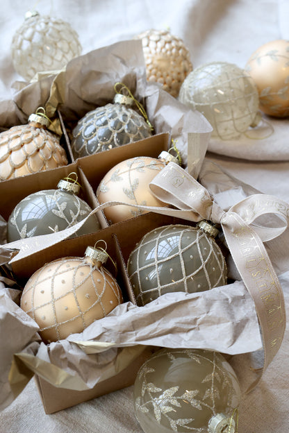 Decorative Christmas ornaments in a box with tissue paper on a light background. Generosa Home