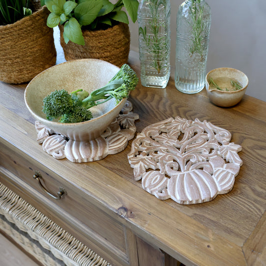 Decorative ceramic items on a wooden surface with plants in the background