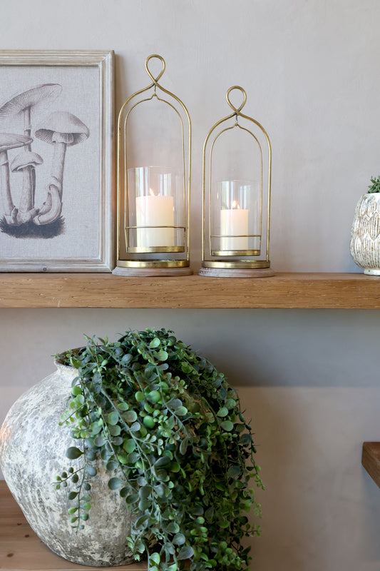 Decorative shelf with gold candle holders, candles, and a framed picture on a neutral wall.