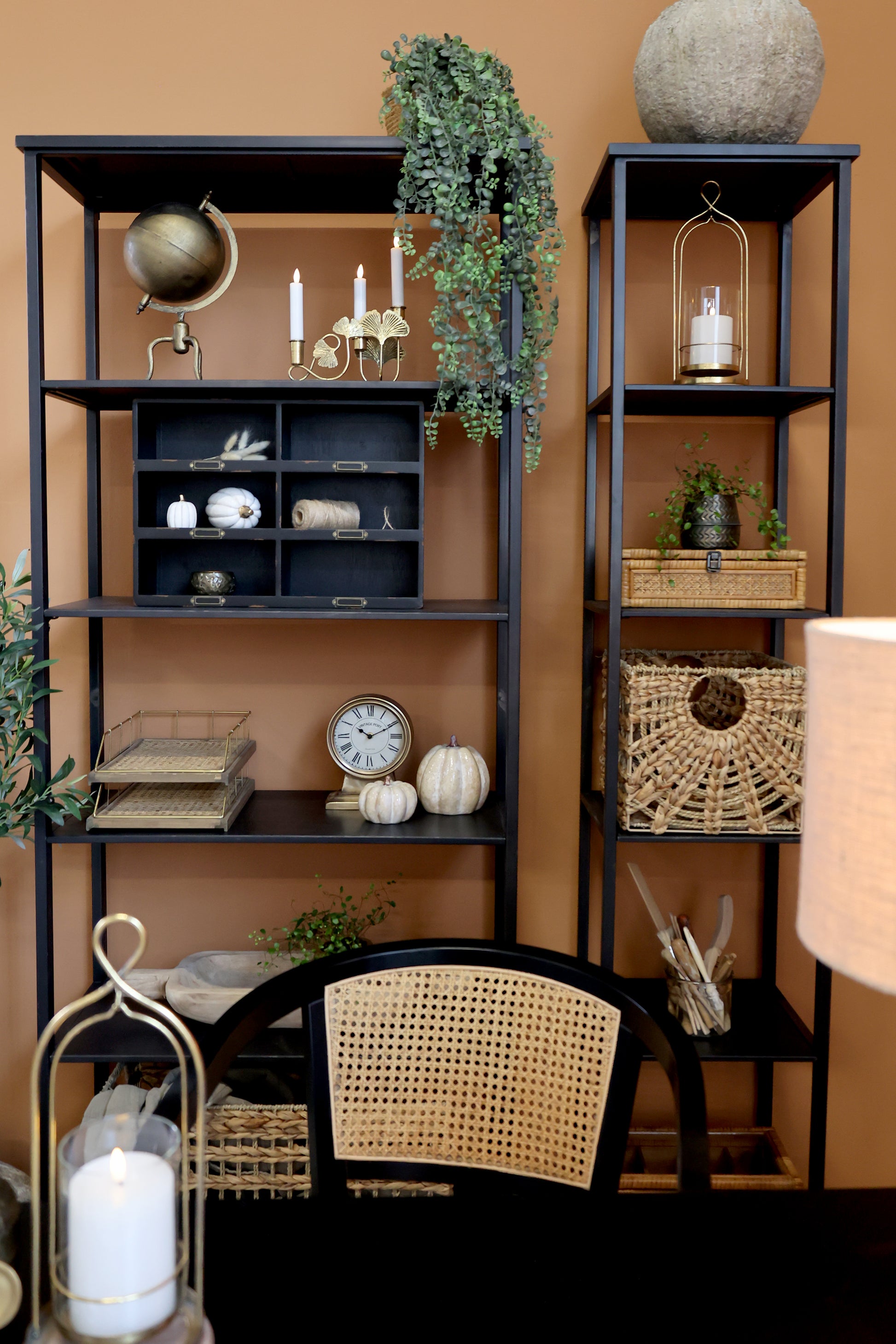 Black shelving units with decorative items against a brown wall
