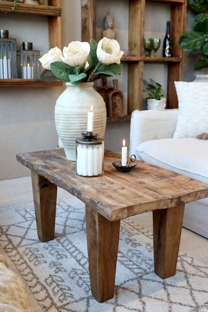 Living room with a wooden coffee table, white vase with flowers, and candles.