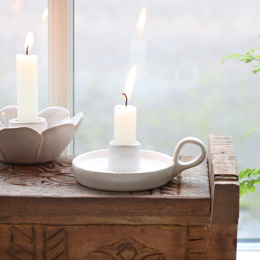 Candle holders with candles on a wooden surface near a window