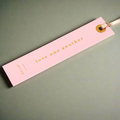 Pink bookmark with 'love one another' text on an open book