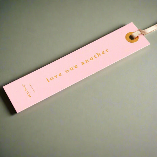 Pink bookmark with 'love one another' text on an open book
