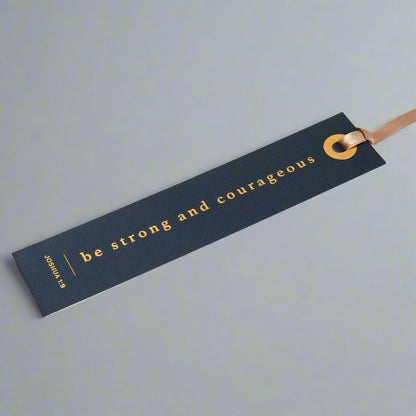 Open book with a blue bookmark featuring 'be strong and courageous' text.
