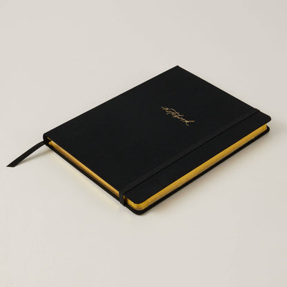 Blush and Gold Black notebook with gold text on a white surface with decorative elements. Generosa Home