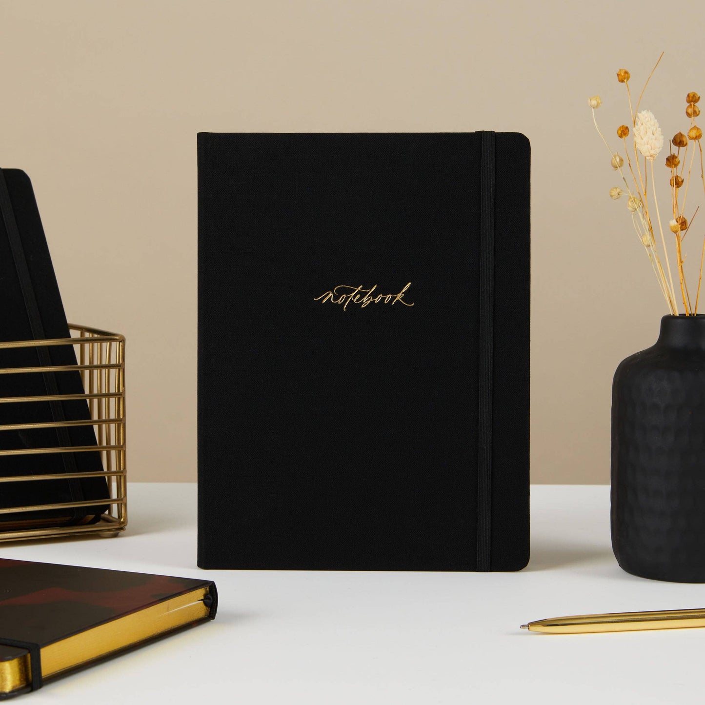 Blush and Gold Black notebook with gold text on a white surface with decorative elements. Generosa Home