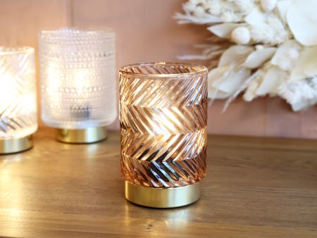 Decorative candle holders on a wooden surface with a blurred floral arrangement in the background. Generosa Home