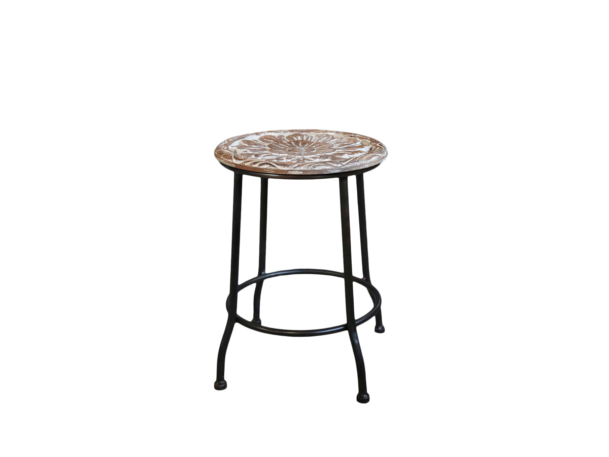 Stool with Flower Seat This stylish and unique stool is the perfect addition to any home. Crafted with a wooden carved flower seat and rubber wood, it boasts a sturdy and reliable metal base and legs. With its unique design and limited availability, it's sure to be a conversation starter.  A beautifully carved, decorative wooden seat on iron legs. A lovely addition to any room.- Generosa